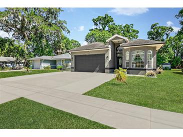 Charming gray single-story home featuring an attached two-car garage, beautiful lawn, and well-manicured landscaping at 535 Madison Ave, Daytona Beach, FL 32114
