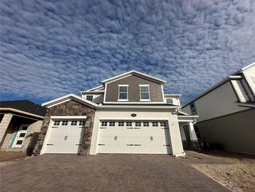 Two-story house with stone accents and a three-car garage at 5274 Teirgarten St, Saint Cloud, FL 34771