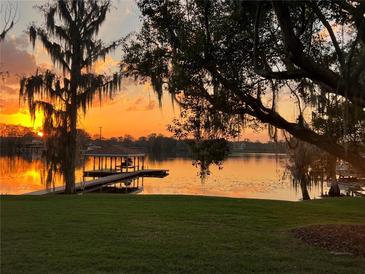 Beautiful lake view at sunset with a dock and boathouse, framed by trees with Spanish moss at 4024 W Danby Ct, Winter Springs, FL 32708