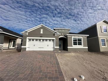 Two-story house with gray exterior, white garage door, and paver driveway at 5292 Teirgarten St, Saint Cloud, FL 34771