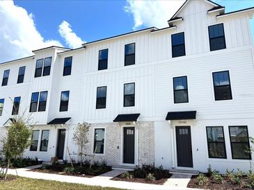 Modern townhouse with white siding, black trim, and well-maintained landscaping at 15106 Grove Lake Dr, Winter Garden, FL 34787