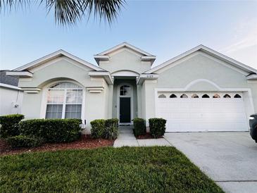 Light green house with a two-car garage and well-manicured lawn at 8169 Fan Palm Way, Kissimmee, FL 34747