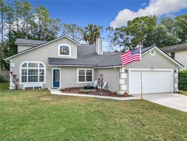 Charming two-story home with a well-manicured lawn and an American flag waving in the breeze at 5240 N Lake Burkett Ln, Winter Park, FL 32792