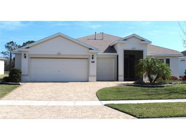 Charming single-story home featuring a well-manicured lawn and a brick-paved driveway leading to a spacious three-car garage at 3621 Arlington Ridge Blvd, Leesburg, FL 34748