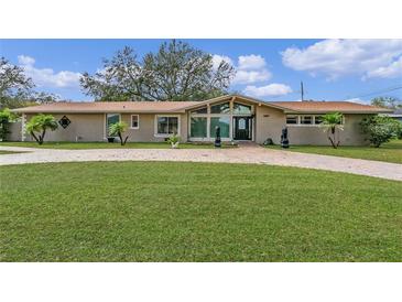 A single-story home with a brick driveway, green lawn, and symmetrical landscaping at 1407 Edgewater Beach Dr, Lakeland, FL 33805