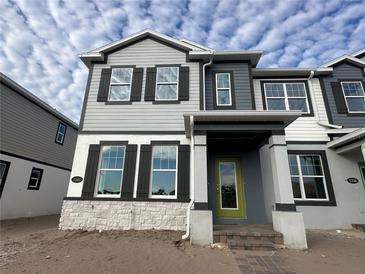 Two-story house with gray and white siding, dark shutters, and a lime green front door at 1360 Lumpini St, St Cloud, FL 34771