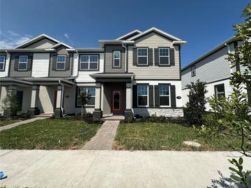 Charming two-story townhome with gray and white facade, dark shutters, and a red front door at 1364 Lumpini St, St Cloud, FL 34771
