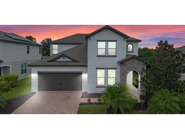 Two-story house with gray siding, stone accents, and a two-car garage at 5353 White Blossom Cir, Saint Cloud, FL 34771