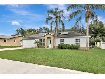 Charming single-story home with a well-manicured lawn, solar panels, and a welcoming light-blue front door at 1053 E Hancock Dr, Deltona, FL 32725