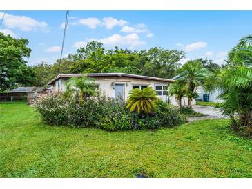 Charming single-story home with lush landscaping, palm trees and vibrant flower beds in a verdant front yard at 4908 Seminole Ave, Winter Park, FL 32792