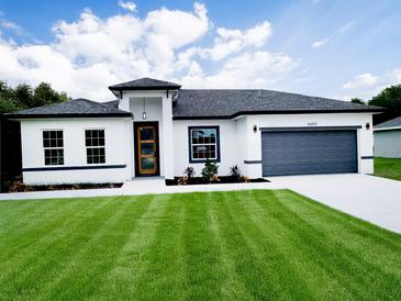 Beautiful single-story home featuring a well-manicured lawn, neutral paint scheme, and attached two-car garage at 16050 Sw 21St Ct, Ocala, FL 34473