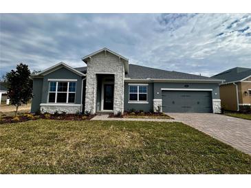 Single-story home with gray siding, stone accents, and a two-car garage at 371 Lady Palm St, Apopka, FL 32703