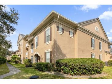 Well-maintained condo with neutral tones, brown shutters, manicured bushes, and green grass at 14304 Fredricksburg Dr # 420, Orlando, FL 32837