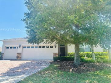Charming single-story home with a well-manicured lawn and a brick-paved driveway leading to a two-car garage at 2871 Sandy Cay St, Clermont, FL 34711