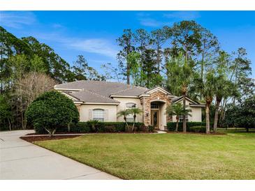 Spacious one-story home with a sprawling lawn, mature landscaping, and a welcoming stone entrance at 943 Elm Harbor Ct, Lake Mary, FL 32746