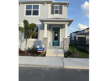 Inviting two-story home with a covered front porch, stone accents, and a teal front door at 1354 Tarflower Dr, Winter Springs, FL 32708