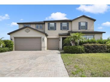 Two-story home with a three-car garage, neutral stucco exterior, blue shutters, a brick driveway, and landscaping at 3303 Kayak Way, Orlando, FL 32820