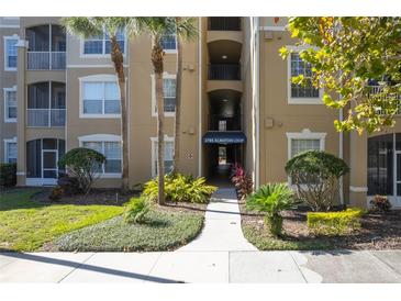 Well-maintained building entrance with lush landscaping and shade trees at 2785 Almaton Loop # 305, Kissimmee, FL 34747