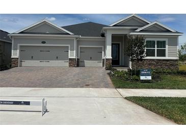 Charming single-Gathering home with a three-car garage and a beautifully paved driveway and stone detailing at 5379 Park Guell St, St Cloud, FL 34771