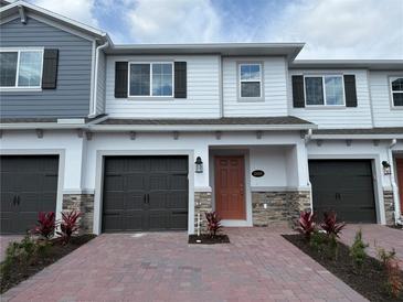 Charming two-story townhome featuring a well-manicured brick entryway and a convenient attached garage at 5086 Rain Shadow Dr, St Cloud, FL 34772