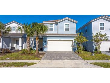 Charming two-story home with a two car garage, tropical landscaping, and a brick paver driveway at 7400 Oakmoss Loop, Davenport, FL 33837