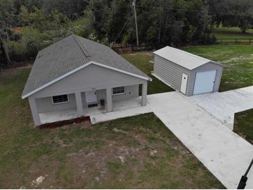Inviting single-story home featuring a metal garage, well-manicured lawn, and a cozy front porch at 9650 Nw Gainesville Rd, Ocala, FL 34475