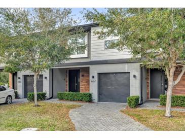 Modern townhome featuring a gray facade, black garage door and a neatly landscaped walkway leading to the front entrance at 4457 Le Reve Ct, Kissimmee, FL 34746