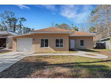 Newly constructed tan house with a white garage door and landscaped lawn at 1740 Palm Rd, Ormond Beach, FL 32174