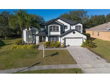 Two-story house with black and white exterior, lush landscaping, and a paved driveway at 4431 Rock Hill Loop, Apopka, FL 32712