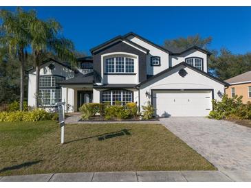 Stunning two-story house with a black and white exterior, lush landscaping, and a paved driveway at 4431 Rock Hill Loop, Apopka, FL 32712