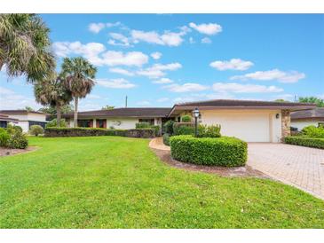 Charming one-story home with mature palm trees, manicured landscaping, and a brick-paved driveway at 10 Pilot Pl, Winter Haven, FL 33881