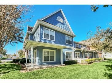 Charming blue two-story townhome featuring a welcoming front porch, bright windows, and a well-manicured lawn at 2203 San Vittorino Cir # 102, Kissimmee, FL 34741