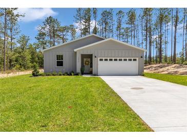 Charming one-story home with gray siding, a manicured lawn, and a concrete driveway at 13516 Sw 78 Pl, Dunnellon, FL 34432