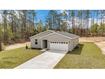 Aerial view of the house, surrounded by mature trees, a long driveway, and a well-maintained lawn at 13516 Sw 78 Pl, Dunnellon, FL 34432