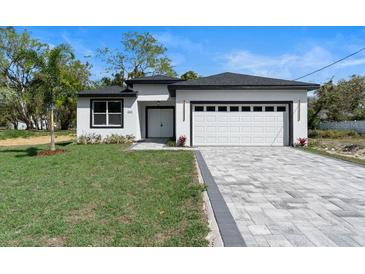 Charming single-story home with a well-manicured lawn and a paved driveway leading to an attached garage at 205 E 17Th St, Apopka, FL 32703