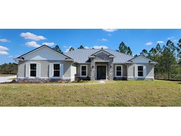 Charming single-story home featuring a metal roof, stone accents, and a well-manicured lawn at 0 Oberly Pkwy, Orlando, FL 32833