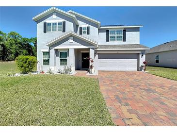 Charming two-story home featuring a well-maintained lawn and brick driveway at 678 Fiddlesticks Dr, Davenport, FL 33837