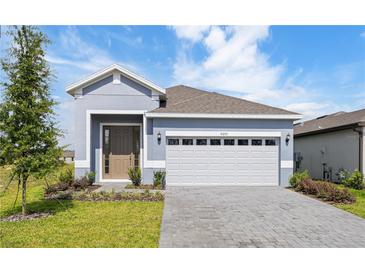 Charming single-story home featuring a paved driveway, manicured lawn, and attached two-car garage at 9097 Wildlight Trl, Wildwood, FL 34785