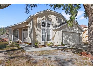 Tan house with white garage door and landscaping at 230 Bay Meadow Dr, Kissimmee, FL 34746
