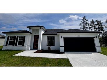 Charming single-story home with a white exterior, dark roof, and well-manicured lawn at 3041 Sw 168Th Loop, Ocala, FL 34473