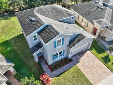 Charming two-story home with a well-manicured lawn, brick driveway, and bright blue shutters at 3207 Stratton Cir, Kissimmee, FL 34744