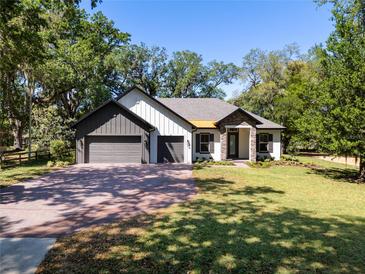 Charming single-story home showcasing a three-car garage and brick driveway, with a well-manicured lawn and landscape at 347 Mission Rd, Oviedo, FL 32765