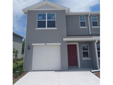 Charming two-story home featuring a one-car garage and a vibrant red front door at 547 Zinfandel Dr, Holly Hill, FL 32117