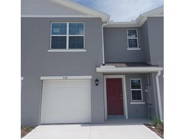 Charming two-story home featuring a white garage door and a welcoming red front door at 541 Zinfandel Dr, Holly Hill, FL 32117