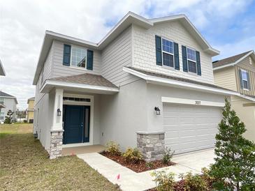 Charming two-story home boasts a covered entryway, a two-car garage, and manicured landscaping at 3037 Tackle Dr, Leesburg, FL 34748