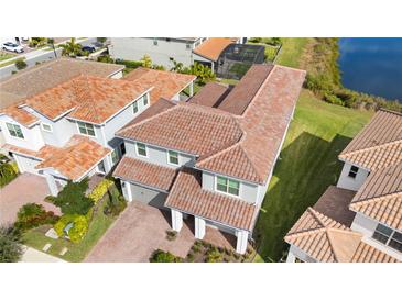 Aerial view of a two-story home featuring a clay tile roof, lush landscaping, and a two-car garage at 13333 Oakenshaw Ln, Orlando, FL 32832