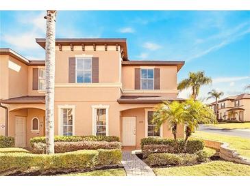 Two-story townhome with attractive landscaping and a paved walkway at 100 Palermo St, Davenport, FL 33897