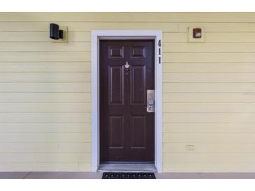A brown front door with a door knocker in a light yellow building at 411 Lucaya Loop # 411, Davenport, FL 33897