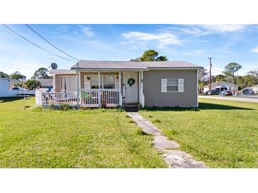 Charming single-story home featuring a covered porch, white picket fence, and a well-maintained front yard at 710 Spruce St, New Smyrna Beach, FL 32168