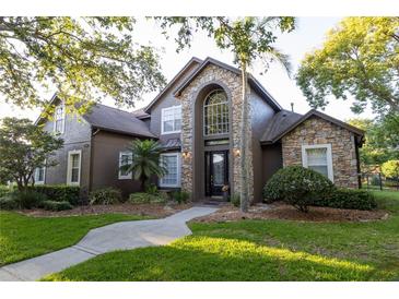 Charming two-story home featuring a stone facade, arched entryway, and manicured lawn at 1912 Westover Reserve Blvd, Windermere, FL 34786